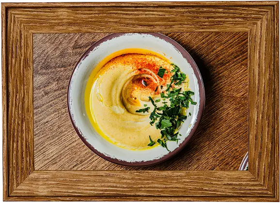 there is a bowl of hummusle with a spoon and a fork