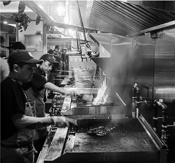 several people are cooking in a kitchen with a lot of smoke