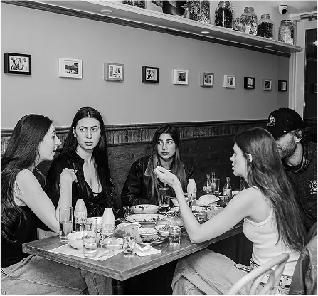 several people sitting at a table with plates of food and drinks